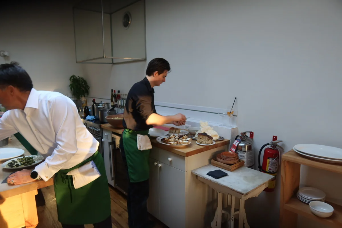 Primo cooks in white shirts and green aprons preparing dishes in a kitchen