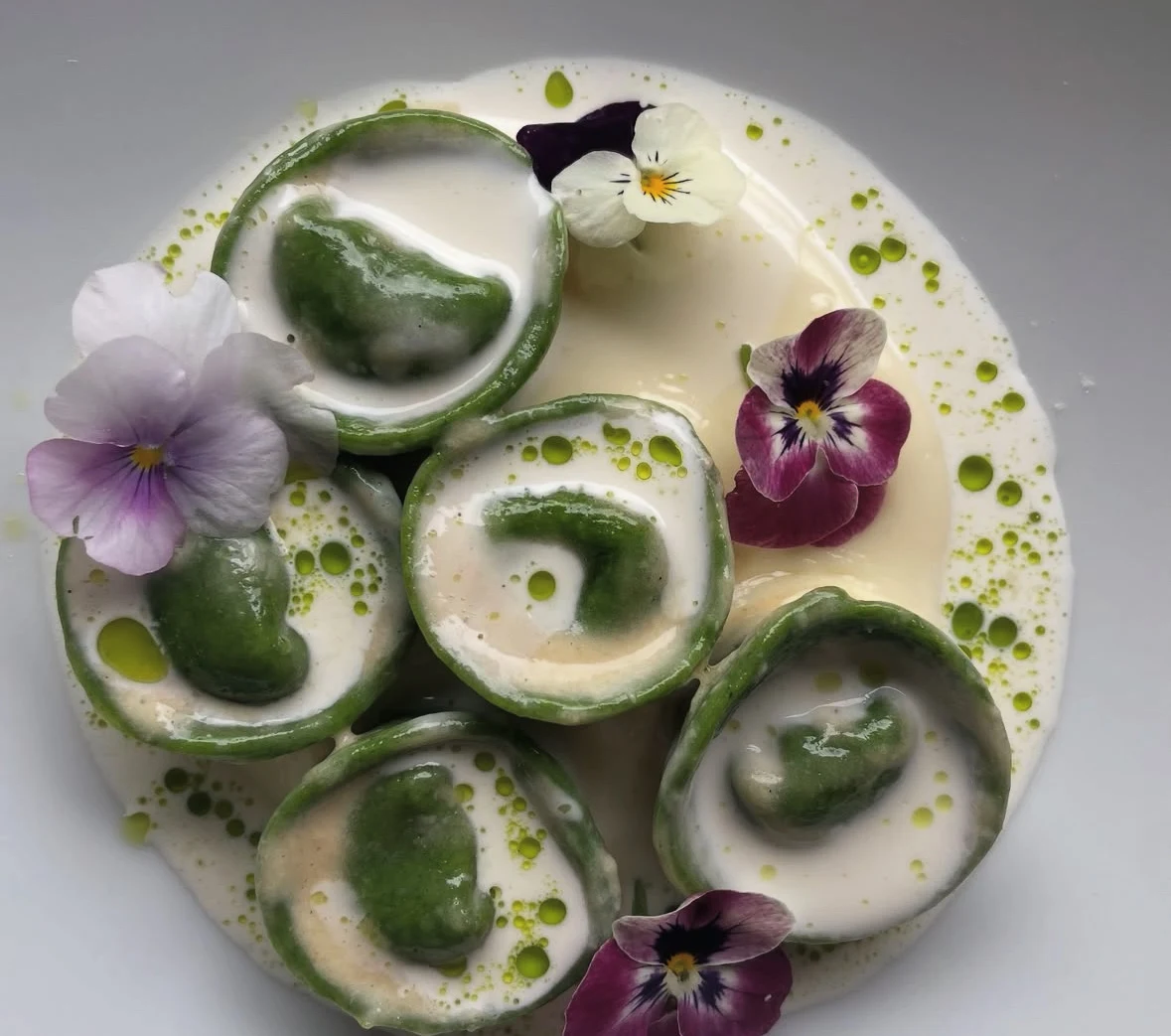 Green filled pasta with pansy flowers and herb oil