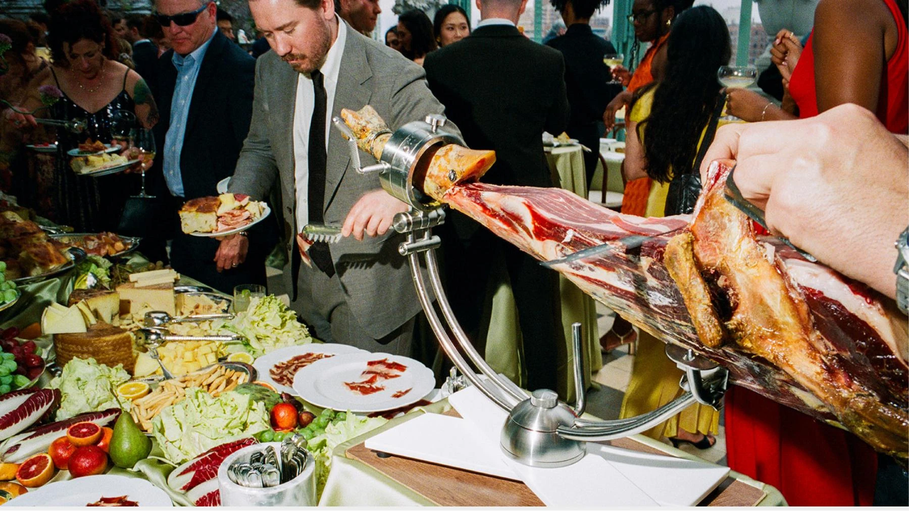 Guests beside a hand-carved cured ham and abundant Primo grazing table