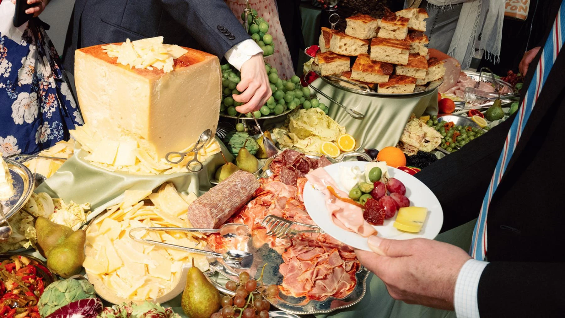 Guests serving focaccia, cheese, fruit, and charcuterie at a Primo event